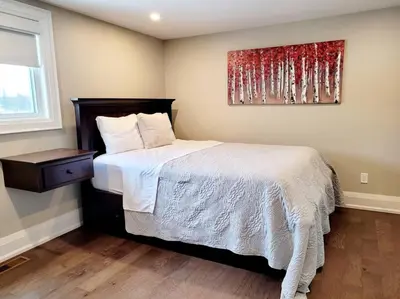 a bedroom with a bed and a painting on the wall at Chemong Lake Waterfront Cottage☆privateboatlaunch in Lakefield