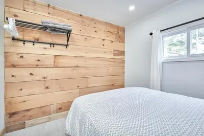 a bedroom with a wooden accent wall and a bed at Muskoka Honey Harbour 4-Bed Retreat with Hot Tub in Honey Harbor