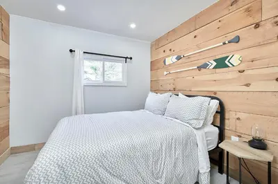 a bedroom with a wooden accent wall and a bed at Muskoka Honey Harbour 4-Bed Retreat with Hot Tub in Honey Harbor