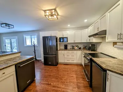 a kitchen with white cabinets and a black refrigerator at Cozy Escape, Kawarthas Cottage With Sauna in Buckhorn