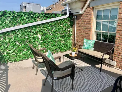 a patio with chairs and a table and a green wall at Suites On King in Niagara on the Lake