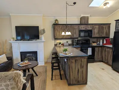 a living room with a kitchen with a fireplace at Suites On King in Niagara on the Lake