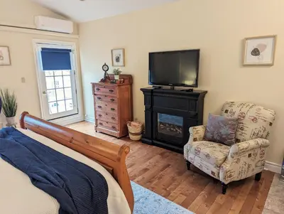 a bedroom with a bed and a television and a chair at Suites On King in Niagara on the Lake