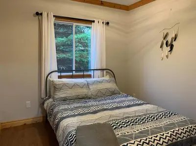 a bedroom with a bed in front of a window at Modern Chic Cottage - Hot Tub, Sauna, Tay Trail in Waubaushene