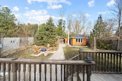 a backyard with a wooden deck and a house at Modern Chic Cottage - Hot Tub, Sauna, Tay Trail in Waubaushene