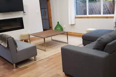 a living room with a couch and a table at Modern Chic Cottage - Hot Tub, Sauna, Tay Trail in Waubaushene