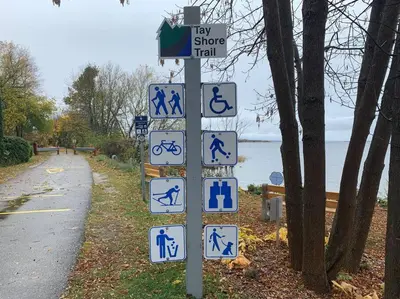 a street sign with blue and white signs on a road at Modern Chic Cottage - Hot Tub, Sauna, Tay Trail in Waubaushene