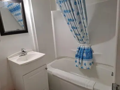 a bathroom with a sink and a toilet and a shower curtain at Three Island Motel in Bobcaygeon