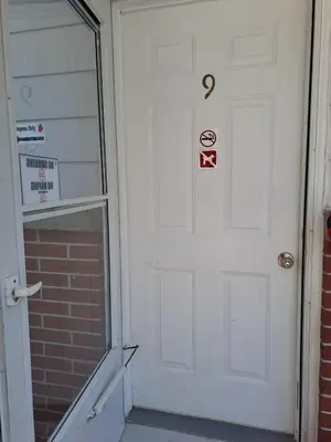 a white door with signs on it next to a brick wall at Three Island Motel in Bobcaygeon