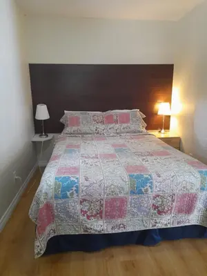 a bed in a bedroom with two lamps and a bedspread at Three Island Motel in Bobcaygeon