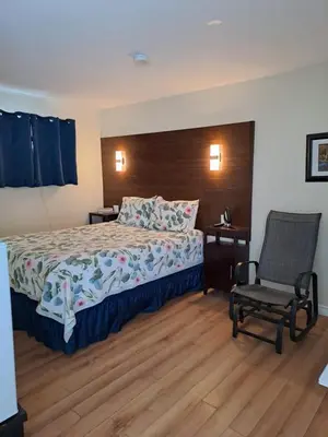 a hotel room with a bed and a chair at Three Island Motel in Bobcaygeon