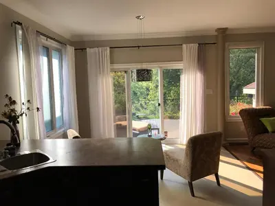 a kitchen with a sink and a living room with windows at Cozy Luxury on the Thames in Ontario! in London