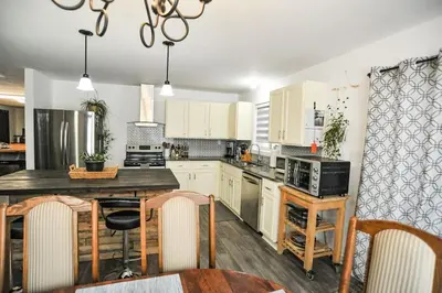 a kitchen with white cabinets and a table with chairs at Modern Rustic Home with Wood Stove & Pool Table in Kemble