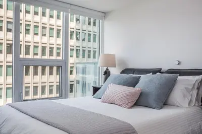 a bedroom with a white bed with a large window at Luxury Condo on Bay Street in Toronto