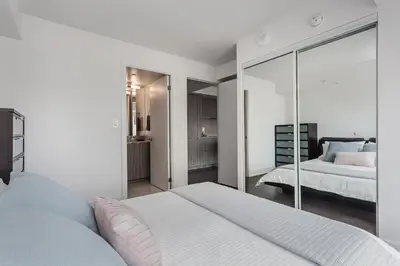a white bedroom with a bed and a mirror at Luxury Condo on Bay Street in Toronto