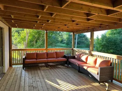 a porch with two couches on a wooden deck at 5 Bedroom Vacation Cottage - King City in Schomberg