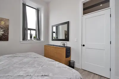a white bedroom with a bed and a mirror at The National on Queen in Saint Marys