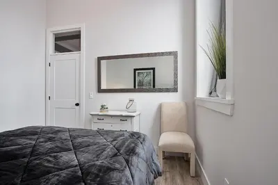a white bedroom with a bed and a chair at The National on Queen in Saint Marys