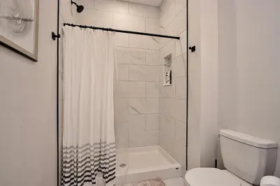 a white bathroom with a shower and a toilet at The National on Queen in Saint Marys