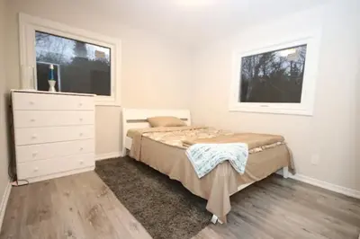 a bedroom with a bed and a dresser and two windows at La Datcha 20 Acres Private Spa, with Pool, Jacuzzi & Wood Burning Sauna in Cookstown