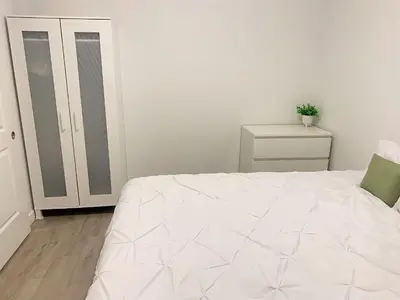 a white bedroom with a bed and a dresser at Cozy 1BR Condo w/ Insuite LDRY, Gym & Free Parking in Waterloo
