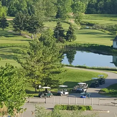 an aerial view of a golf course with golf carts and a pond at Executive House easy access to Kitchener-Waterloo, Cambridge, Toronto, walk to restaurants in Kitchener