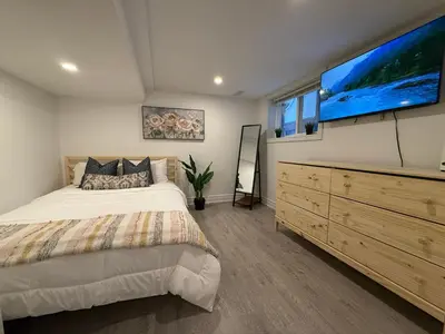 a bedroom with a bed and a large flat screen tv at Modern 2BR in the Heart of Little Italy in Toronto