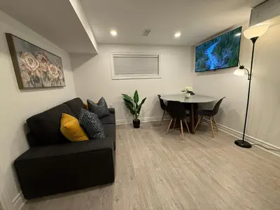 a living room with a black couch and a table at Modern 2BR in the Heart of Little Italy in Toronto