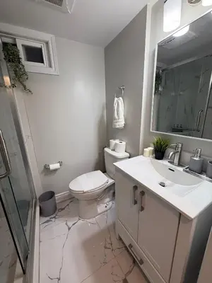 a white bathroom with a toilet and a sink at Modern 2BR in the Heart of Little Italy in Toronto