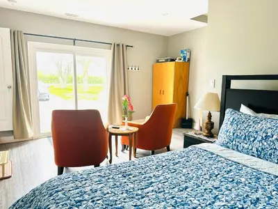 a bedroom with a bed and chairs and a window at Cozy 3-bedroom farmhouse in wine-country in Niagara on the Lake