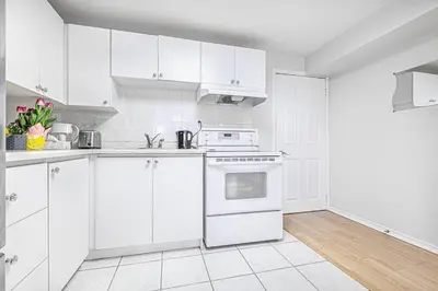 a white kitchen with white cabinets and an oven at Comfortable Apartment in Richmond Hill in Richmond Hill