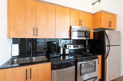 a kitchen with stainless steel appliances and wooden cabinets at Beautiful Modern Toronto Luxurious Scotiabank Arena in Toronto