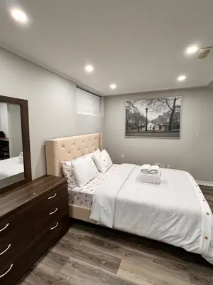 a bedroom with a bed with a dresser and a mirror at The Hestia Kitchener in Kitchener