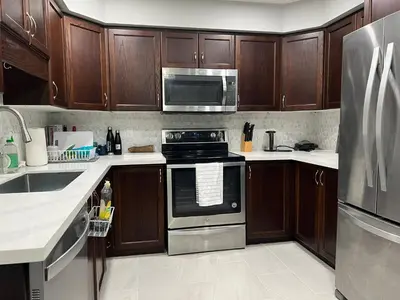 a kitchen with wooden cabinets and stainless steel appliances at The Hestia Kitchener in Kitchener