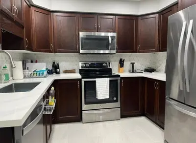 a kitchen with wooden cabinets and stainless steel appliances at The Hestia Kitchener in Kitchener