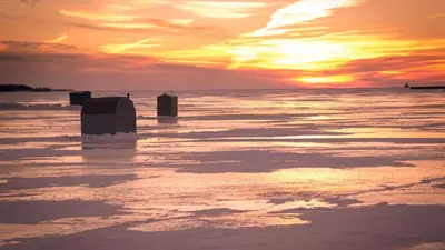 a sunset on the ice in the water at Impressive Modern Waterfront Home on Georgian Bay in Port McNicoll
