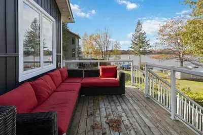 a red couch sitting on the deck of a house at Impressive Modern Waterfront Home on Georgian Bay in Port McNicoll