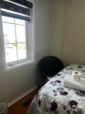 a bedroom with a bed and a chair and a window at Cozy private room in Brampton