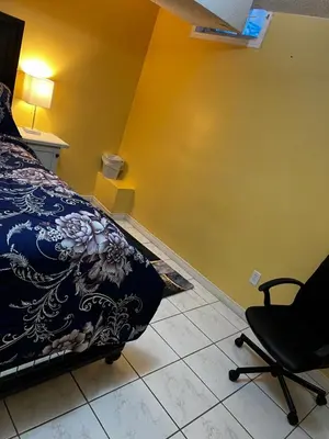 a bedroom with a bed and a chair and a yellow wall at Cozy private room in Brampton