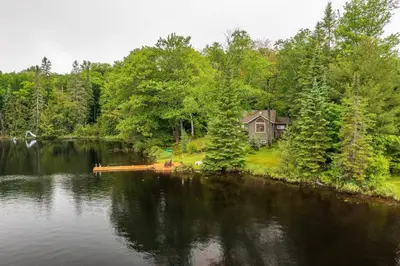 a house on the shore of a lake at Bear Essentials Hideaway in Huntsville