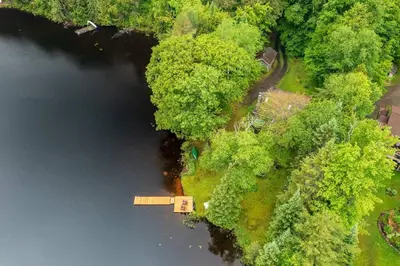 an aerial view of a lake with trees and a house at Bear Essentials Hideaway in Huntsville