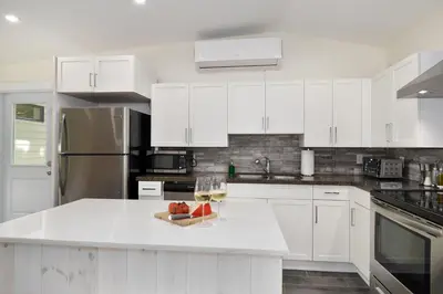 a white kitchen with a bowl of fruit on a counter at Disconnect From Reality/ River House/Hot Tub/Pet Friendly in Port Burwell
