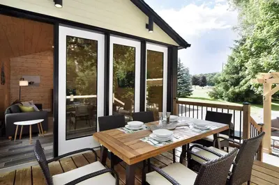 a screened porch with a wooden table and chairs at Disconnect From Reality/ River House/Hot Tub/Pet Friendly in Port Burwell