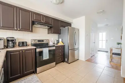 a kitchen with wooden cabinets and stainless steel appliances at GlobalStay 3 Bedroom Townhouse Near Niagara Falls Brock University in Thorold