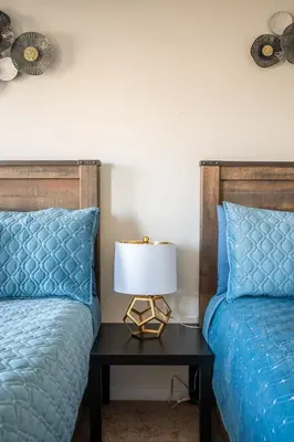 two beds with blue pillows and a table with a lamp at GlobalStay 3 Bedroom Townhouse Near Niagara Falls Brock University in Thorold