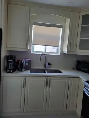 a kitchen with white cabinets and a sink and a window at Maxwell Esabu in Toronto