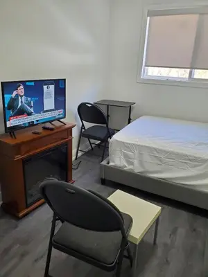 a bedroom with a bed and a tv and a chair at Maxwell Esabu in Toronto