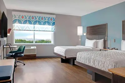 a hotel room with two beds and a chair and a window at Tru By Hilton Toronto Airport West in Mississauga