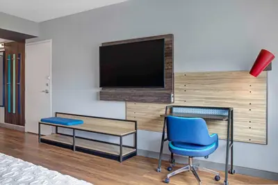 a room with a desk and a tv and a blue chair at Tru By Hilton Toronto Airport West in Mississauga