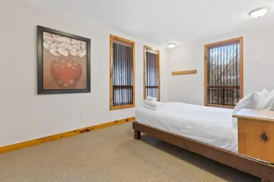 a bedroom with a bed and two windows at 3 Level Ski Chalet 7BR w Deck, Sauna & Ping-Pong! in Blue Mountains